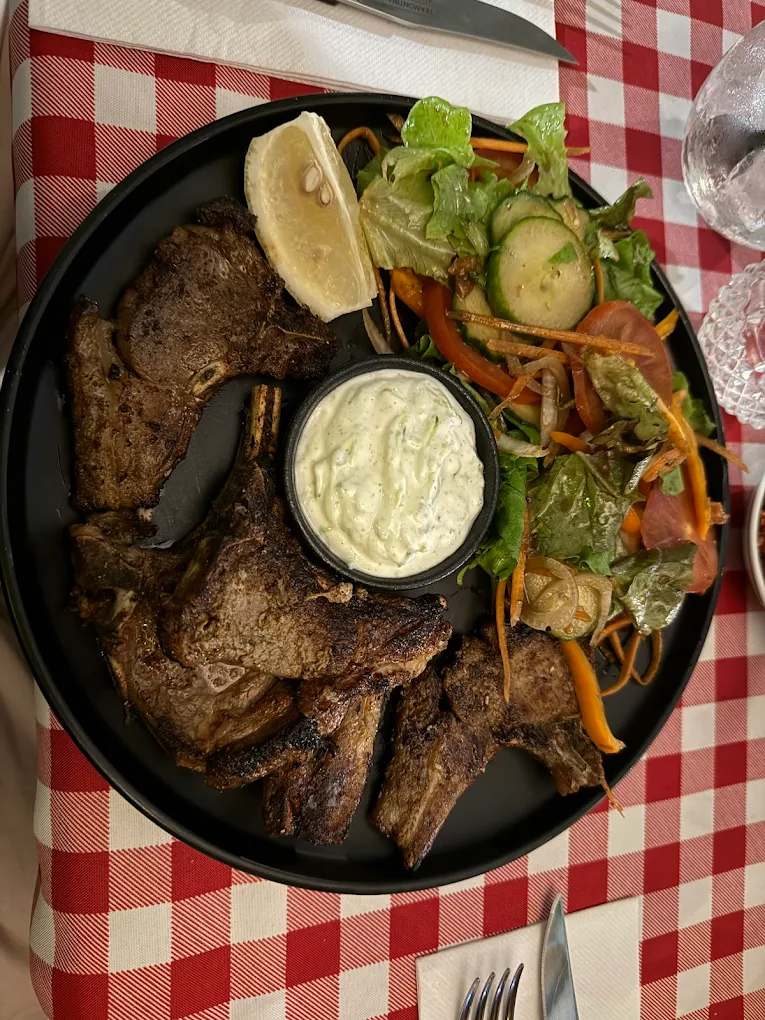 Grilled lamb chops served with salad, lemon and creamy sauce