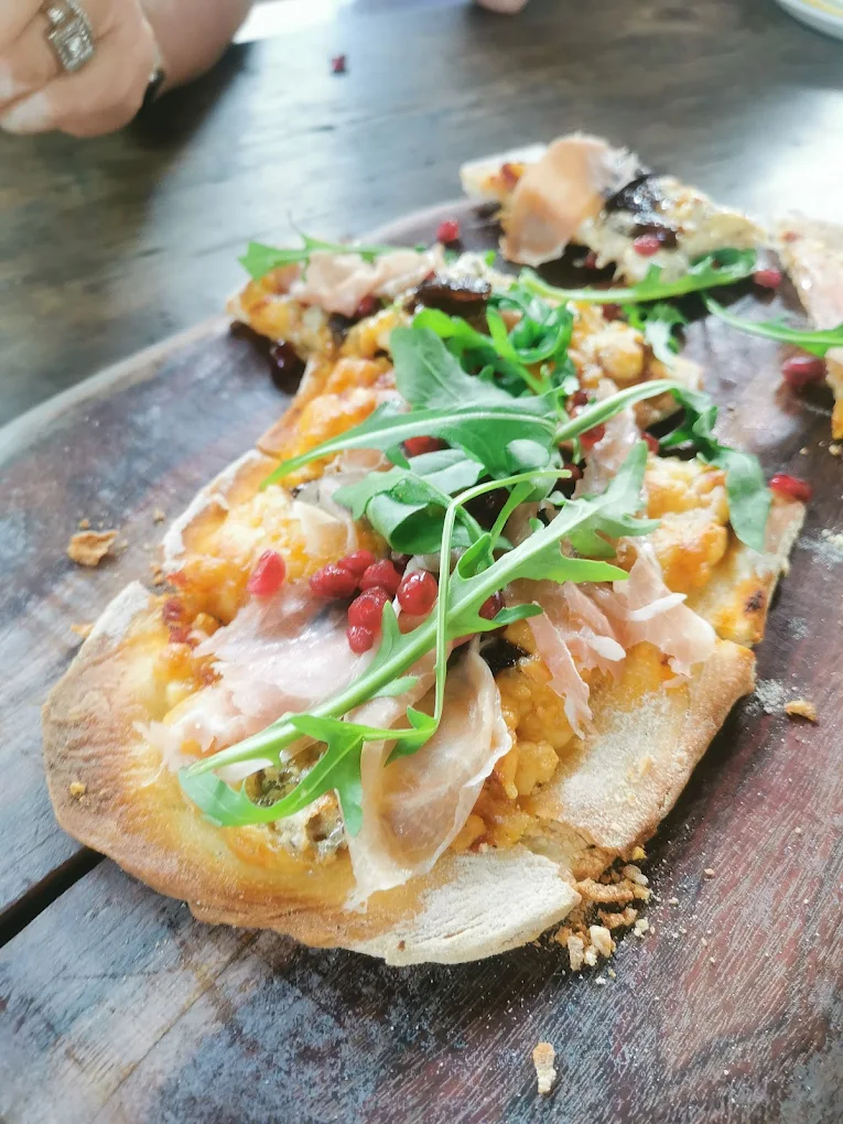 Flatbread topped with greens, cured meat and parmesan at Abbiocco